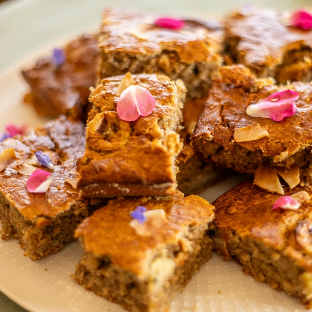 Freshly baked banana bread squares garnished with rose leaves.