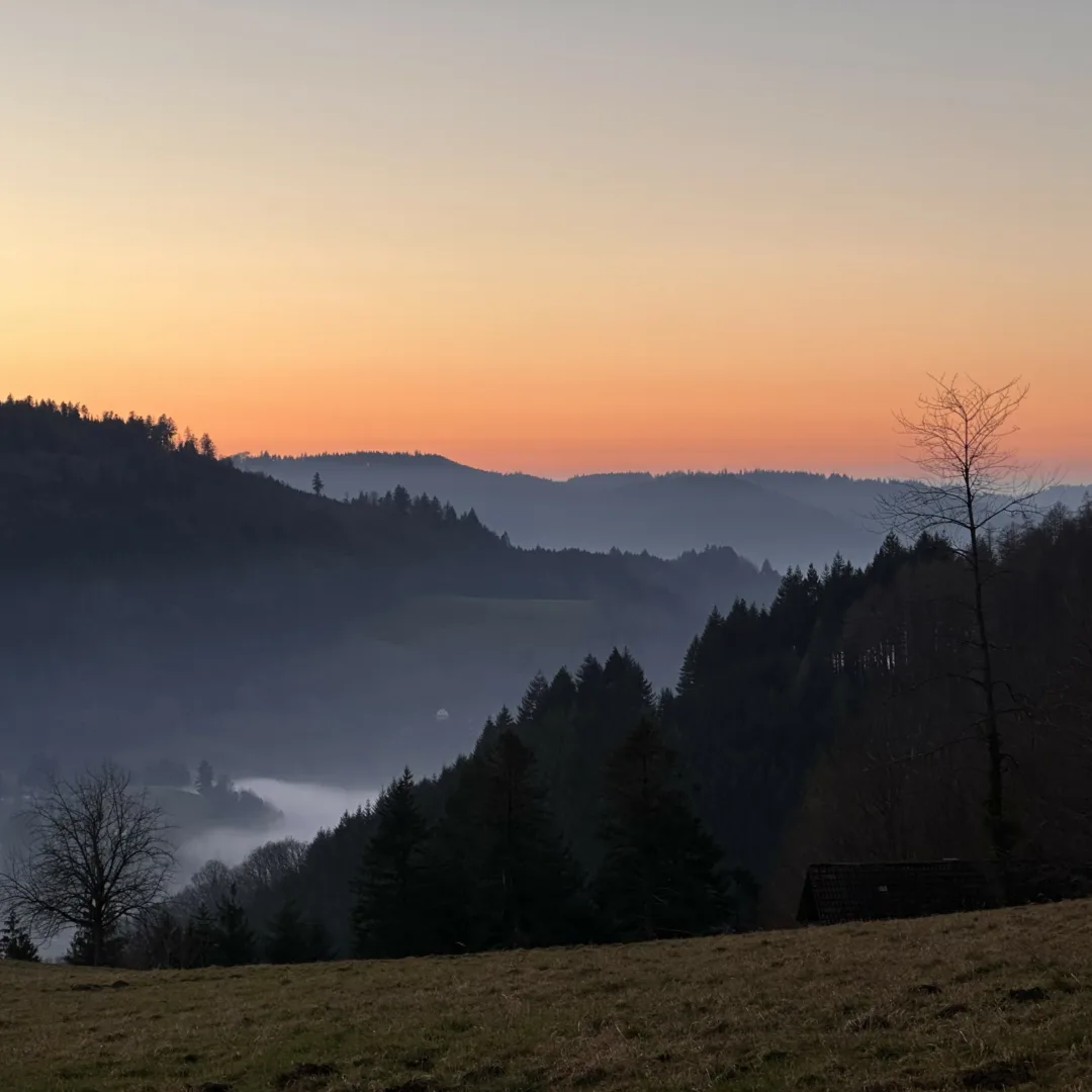 A view of mountains showcasing atmospheric perspective, set against a vibrant orange sky.