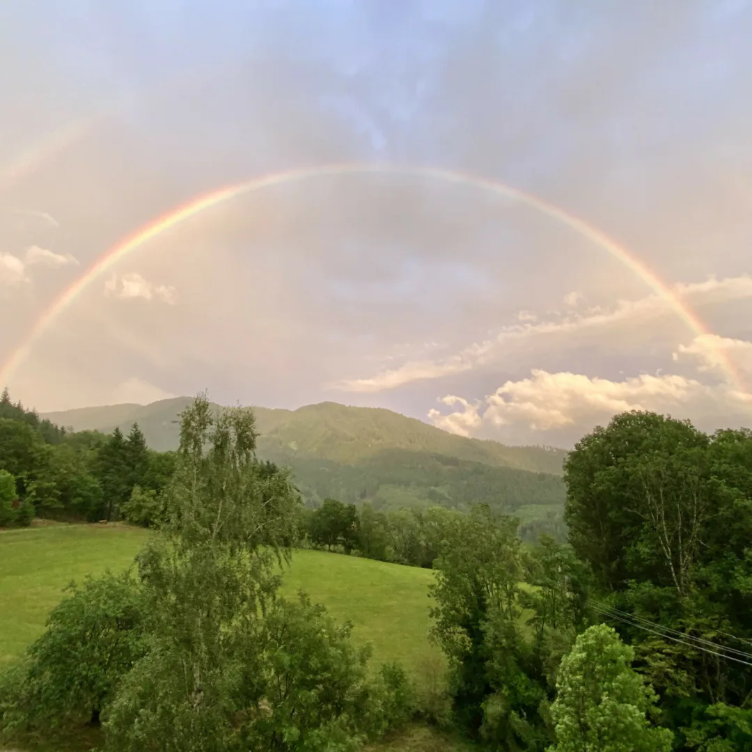 The view from the retreat center, featuring a rainbow, a partially cloudy sky, and surrounding mountains bathed in pastel colors.