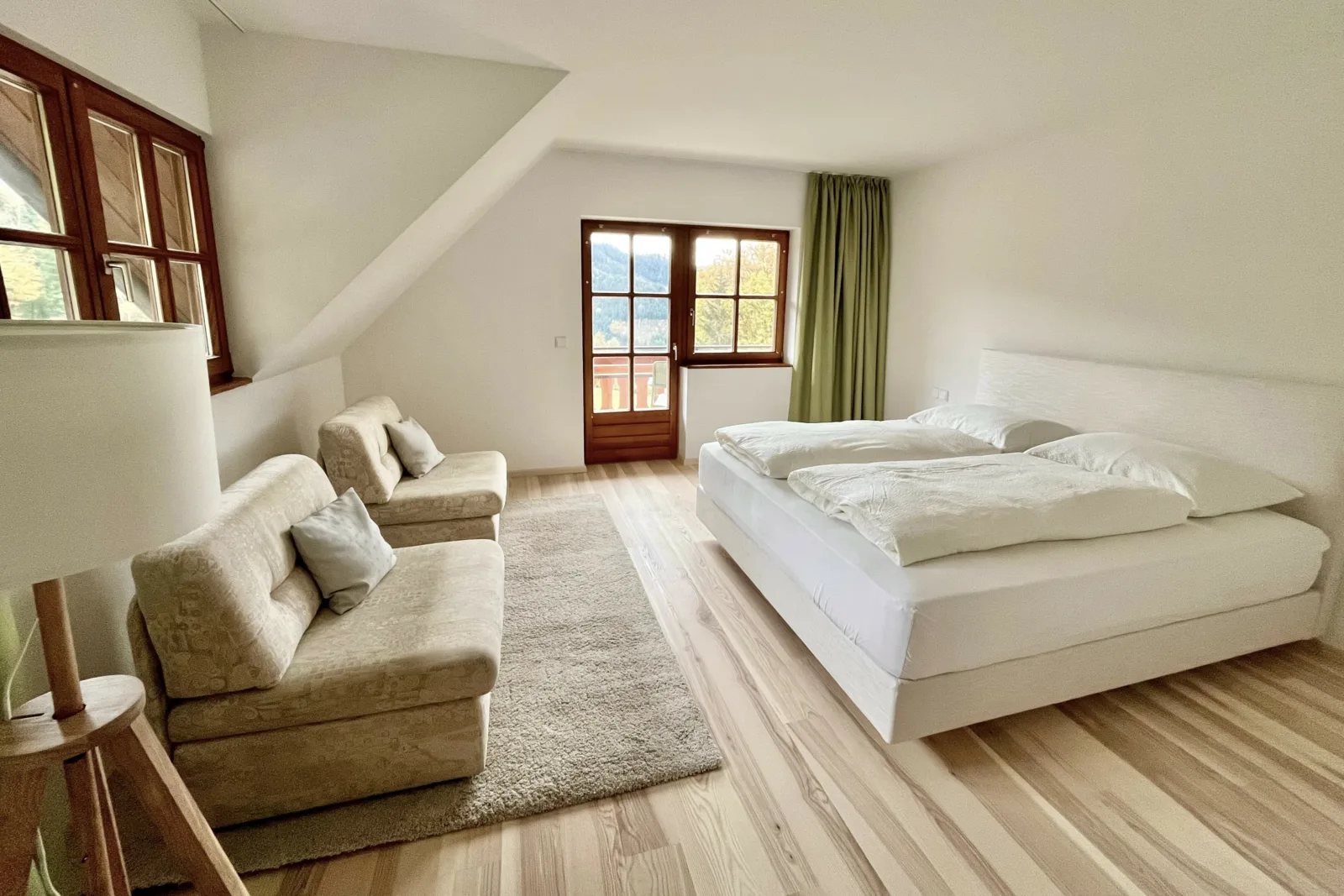 The natural-colored suite, featuring a double bed, sofa chairs and ash-wood flooring.