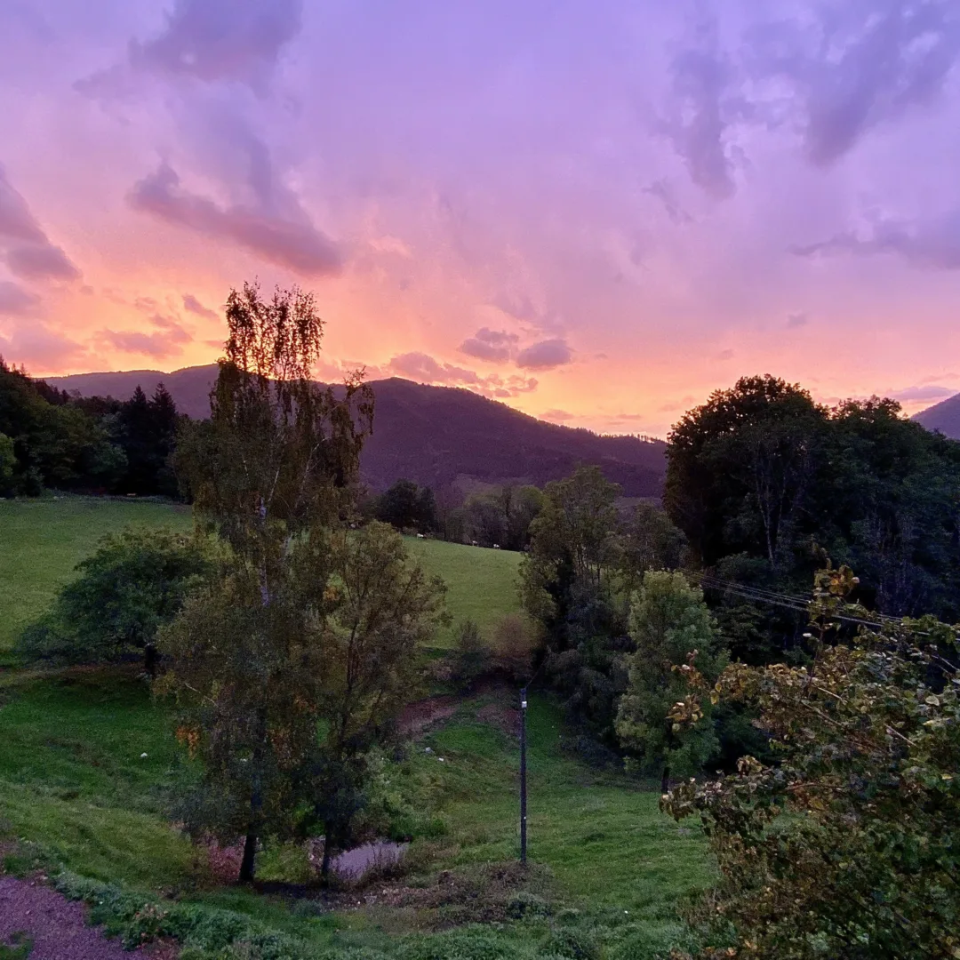 The view from the retreat center with the sunrise painting the sky in lilac and peach hues over the tranquil landscape.