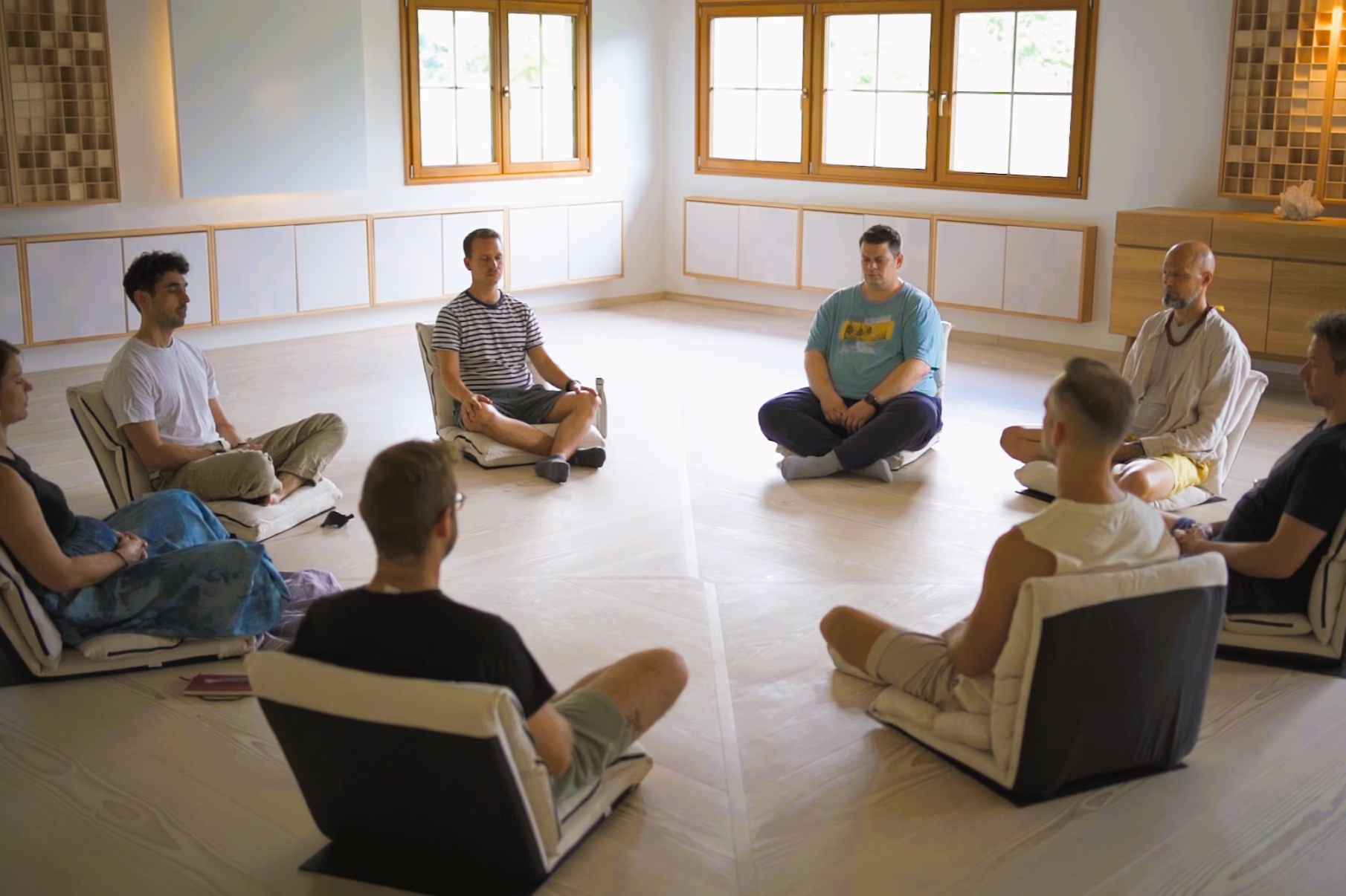 Meditating group, in a circle on meditation chairs.